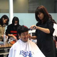 美髮沙龍店長黃鈺茹(右)正在為西原良治同學(左)理髮